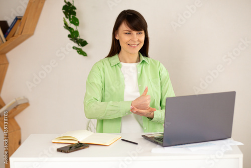Young deaf woman actively participating in a virtual online conference with her employees. Woman is talking on a video call, using sign language and showing gestures to communicate effectively.