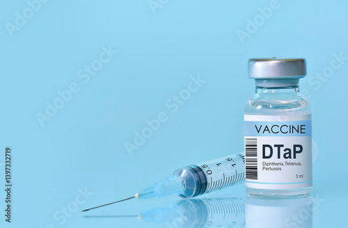 Fototapeta Naklejka Na Ścianę i Meble -  Vaccine for DTaP diphtheria, tetanus,Pertussis in a bottle with a syringe on a blue background. Concept of healthcare, immunization, medical protection, and scientific research in medicine. Copy space