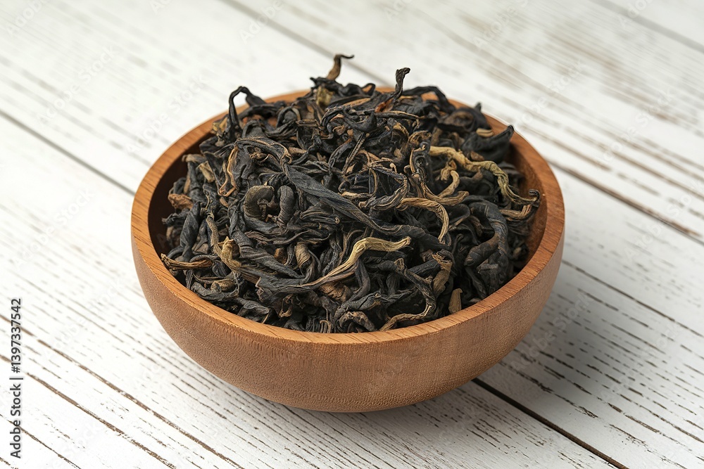 Fototapeta premium A photo of a wooden bowl filled with black, dried tea leaves