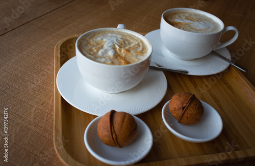 Obraz na płótnie Two white coffee cups with sweet pastry in wooden tray. Breakfast flat lay. Morning aroma coffee and dessert. Americano with milk and biscuits. Elegant lifestyle. Hot aroma cups and cookies. w salonie
