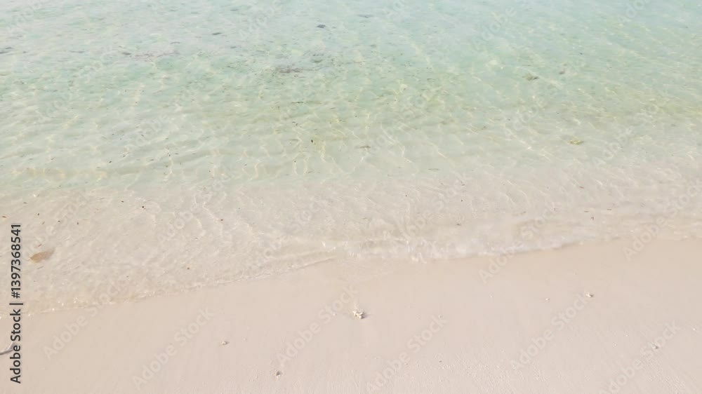 Small waves of clear turquoise ocean water and sandy beach, close up. Tropical nature background Small waves of clear turquoise ocean water and sandy beach, close up. Tropical nature background