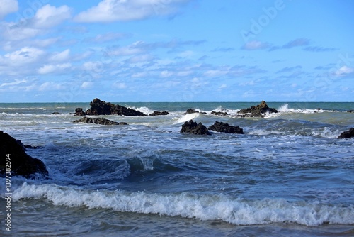 Blue sea with waves breaking near the sand of Coqueiros beach in the Joao Pessoa region, Northeast of Brazil. Sunny day with shadows and light over the water.