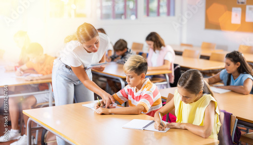 Group of preteen schoolchildren diligently working in class, making notes of teacher lecture..