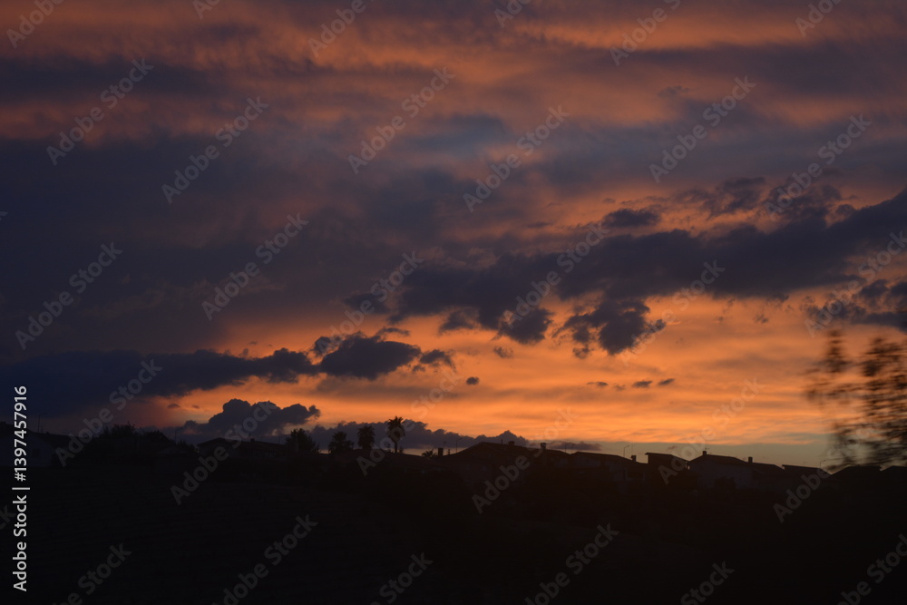 Beautiful sunset with vibrant colors and silhouette of buildings against the horizon in a tranquil evening sky Beautiful sunset with vibrant colors and silhouette of buildings against the horizon in a tranquil evening sky