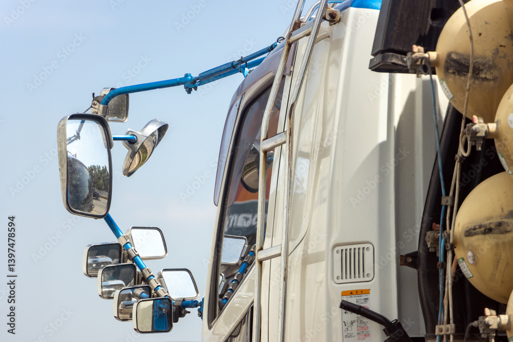 The steel holder with rear-view mirrors attached on the cabin of truck riding on the highway.
