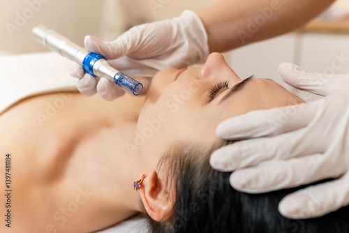 Cosmetologist doing microneedling, patient care using dermapen in a beauty salon