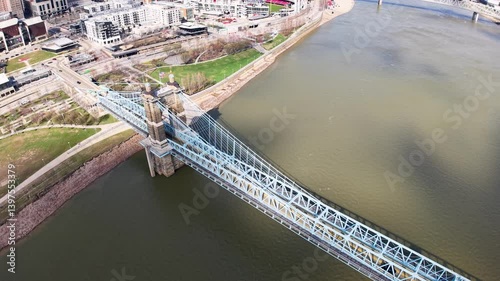 Aerial drone view of a long bridge crossing the Ohio River, connecting green riverbanks and industrial zones under daylight photo