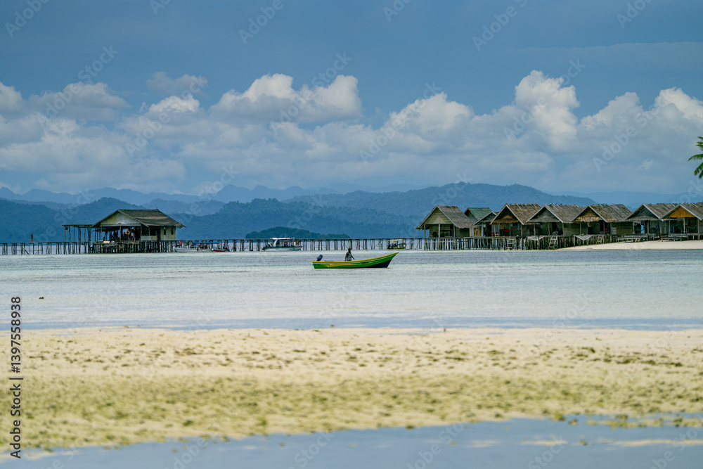 Small boat floats near line of wooden huts over shallow water on a calm tropical beach Small boat floats near line of wooden huts over shallow water on a calm tropical beach