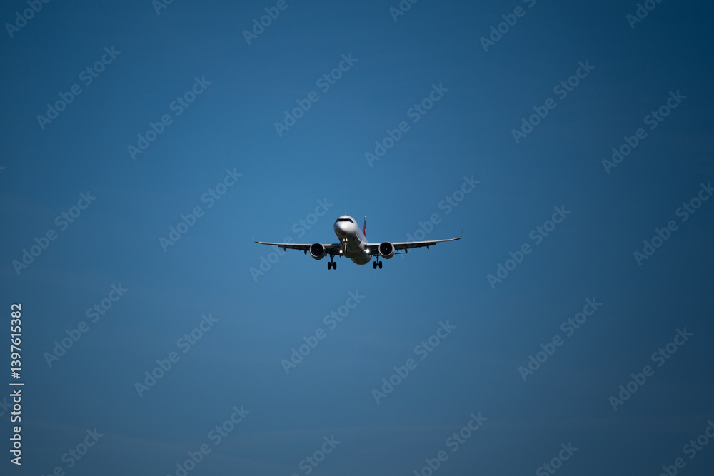 A landing commercial airplane set against blue sky background. Looking up, close up telephoto shot A landing commercial airplane set against blue sky background. Looking up, close up telephoto shot