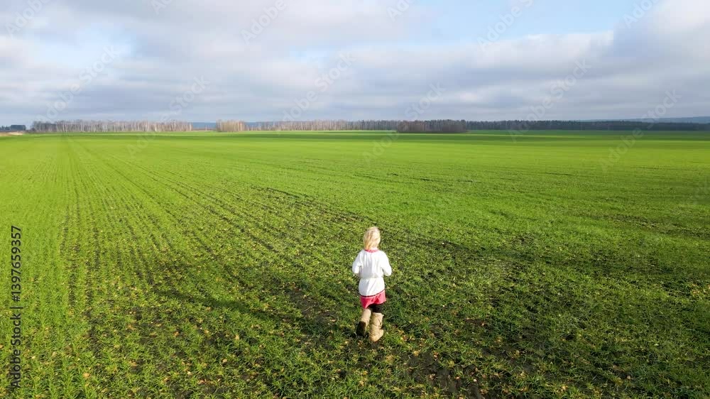 A young child joyfully explores a wide green field surrounded by distant trees. The sky is overcast, reflecting a serene autumn day. The scene captures a sense of adventure and freedom A young child joyfully explores a wide green field surrounded by distant trees. The sky is overcast, reflecting a serene autumn day. The scene captures a sense of adventure and freedom
