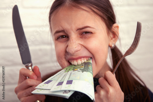 Beautiful serious young girl eating Euro banknotes. She is verry hungry. Business concept. photo