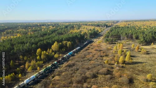 Freight train ride through vibrant autumn landscape in remote wilderness. Lush green trees contrast beautifully with golden foliage