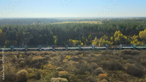 Move together chase the freight train ride through vibrant autumn landscape in remote wilderness. Lush green trees contrast beautifully with golden foliage