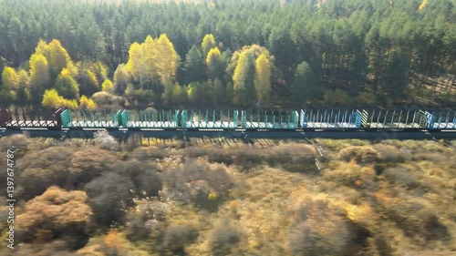 Move together chase the freight train ride through vibrant autumn landscape in remote wilderness. Lush green trees contrast beautifully with golden foliage