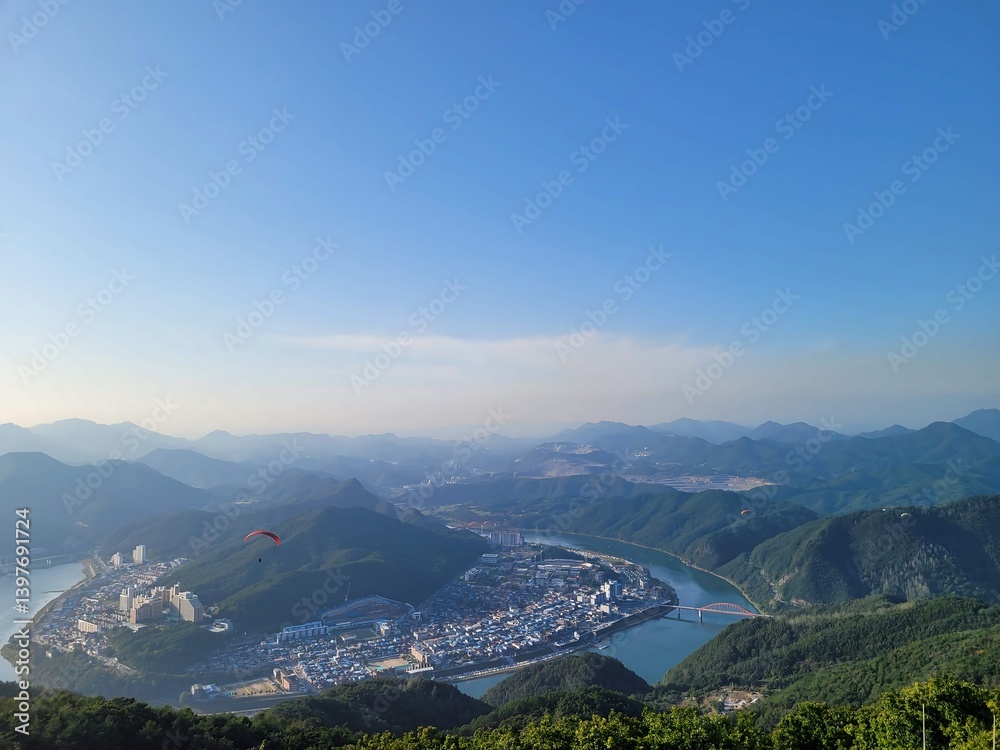 Fototapeta premium El parapente que se disfruta en la cima de la montaña con vistas al río y la montaña.