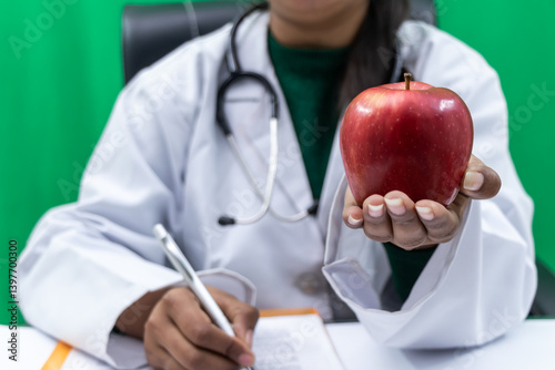 Female doctor offering red apple closeup - Concept of healthy food and nutrition.