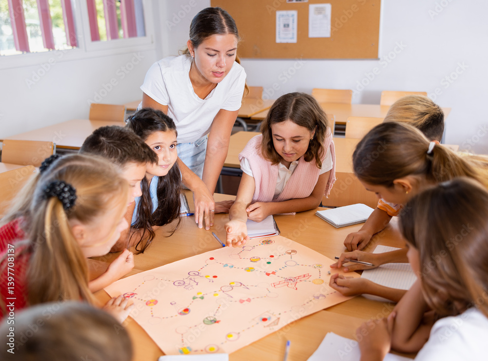 Teacher and schoolchildren play a table game in school class