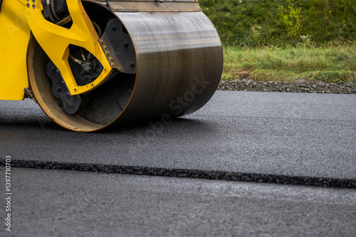 Obraz na płótnie Heavy yellow asphalt road roller with heavy vibration roller compactor that press new hot asphalt on the roadway on a road construction site. w salonie