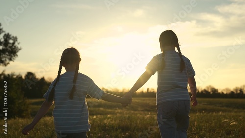 Foto Two child sister girl kid holding hands field sunset, siblings watching sunset t