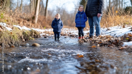 Family enjoying a winter creek walk. Kids splashing in shallow stream