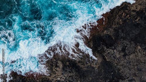 Aerial view of volcanic coast with crashing waves and rocky landscape, Lanzarote island, Canary Islands, Spain.