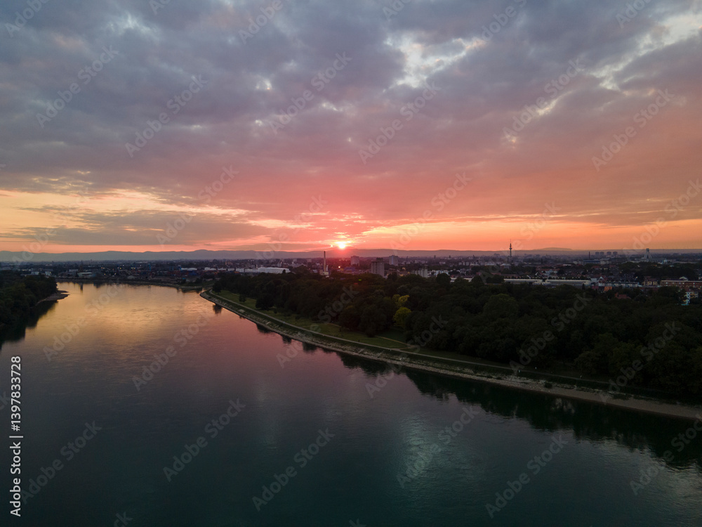 Aerial view of a beautiful sunset over the serene Necakar River with a picturesque cityscape and lush green forest, Mannheim, Baden Wuttermberg, Germany. Aerial view of a beautiful sunset over the serene Necakar River with a picturesque cityscape and lush green forest, Mannheim, Baden Wuttermberg, Germany.