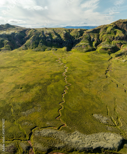 Aerial view of beautiful landscape featuring a yellow river winding through a scenic valley surrounded by mountains and greenery, Olfus, Southern Region, Iceland.