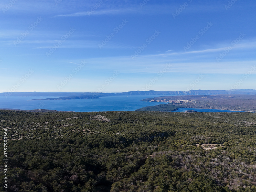 Aerial view of serene forest meeting the tranquil sea along a picturesque coastline, Baska, Primorje-Gorski Kotar, Croatia. Aerial view of serene forest meeting the tranquil sea along a picturesque coastline, Baska, Primorje-Gorski Kotar, Croatia.
