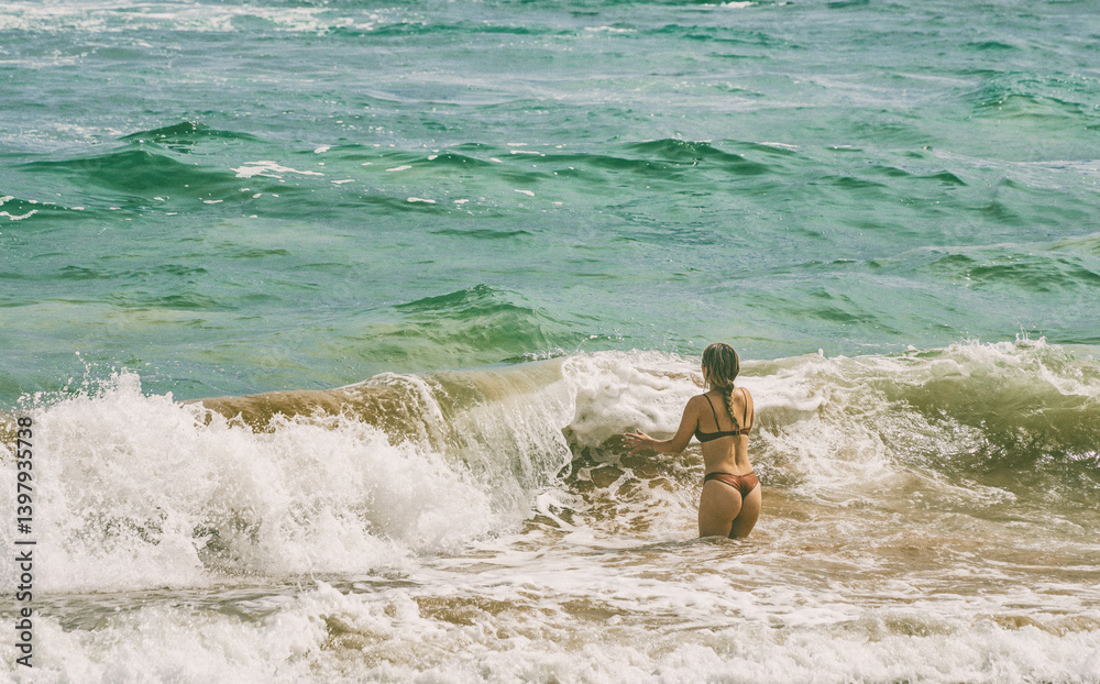 Beautiful young girl enjoying the waves of the ocean