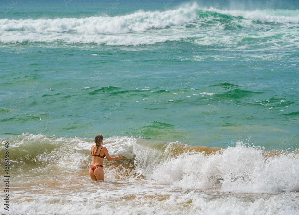 Beautiful young girl enjoying the waves of the ocean