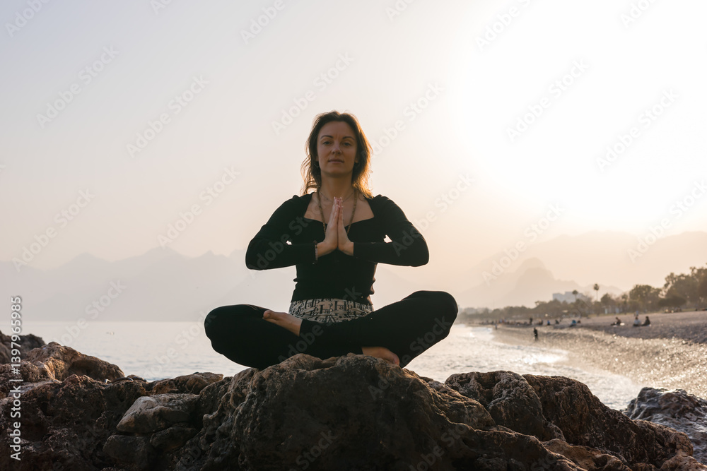 Practicing yoga on rocky beach at sunrise for relaxation and mindfulness Practicing yoga on rocky beach at sunrise for relaxation and mindfulness