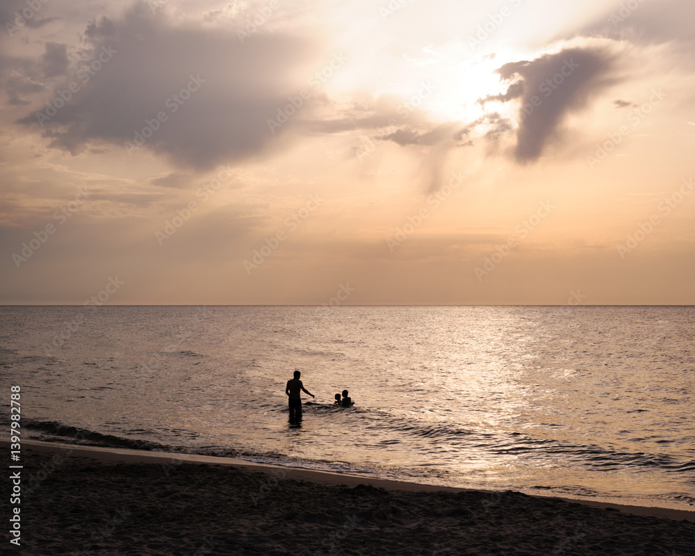 Fototapeta premium People Silhouetted in the Ocean at Sunset
