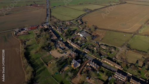 A picturesque aerial view of a charming rural village in the UK, surrounded by extensive farmland photo