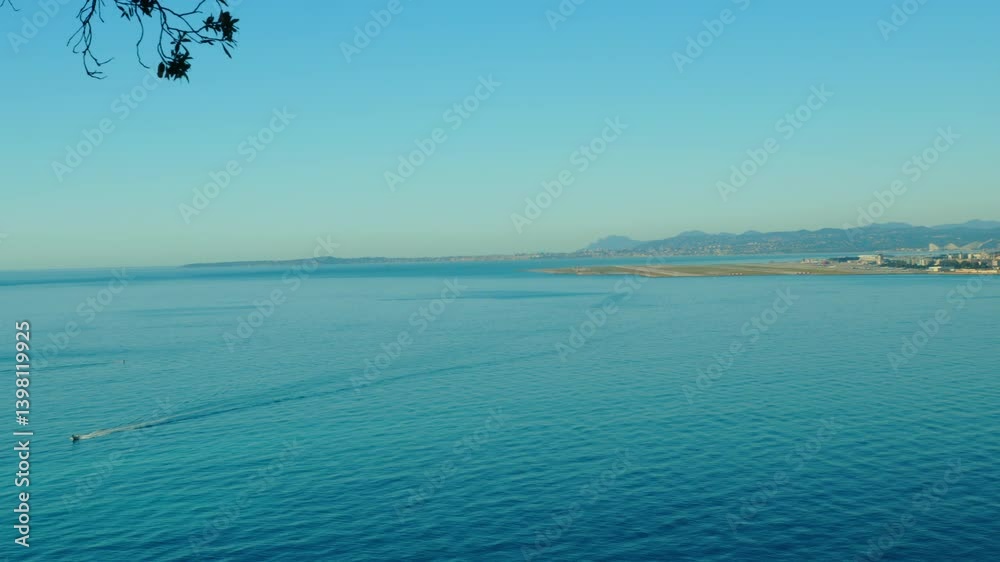 4K Nice French Riviera small boat sailing across the coastline with view of the airport in the background and pan towards the beautiful Baie des Anges