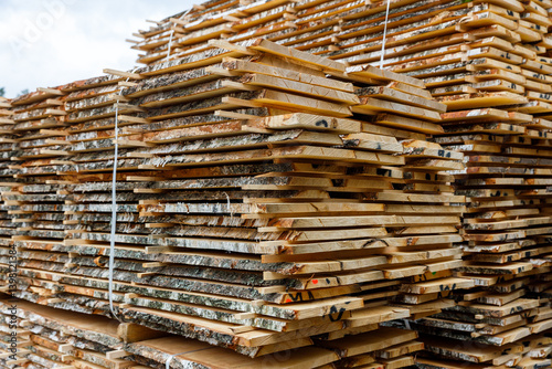 Stacks of Sawn Lumber Boards at Outdoor Sawmill, Large piles of rough sawn wooden planks stacked outdoors at a sawmill.