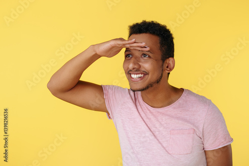 Handsome african american young man looking far away over yellow background.