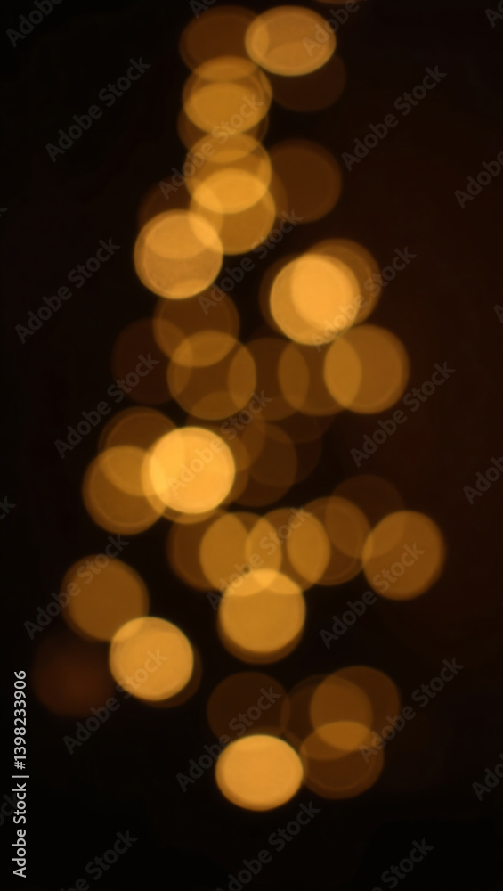 Fototapeta premium Golden bokeh lights shaped like a Christmas tree against a dark background, creating a festive, blurred effect