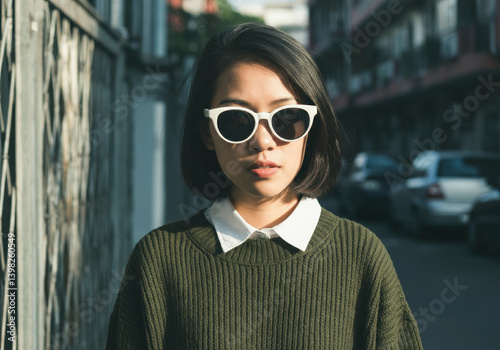 Obraz na płótnie Woman with white sunglasses on urban street. AI-generated fashion scene with retro style, streetwear energy and contemporary editorial aesthetics in natural lighting. w salonie