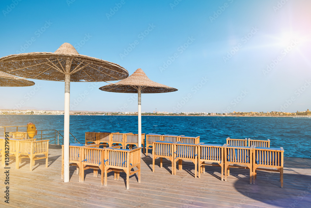 Fototapeta premium Wooden pier on sea stretching into distance beyond horizon on sunny summer day. Vacation and Travel Concept.