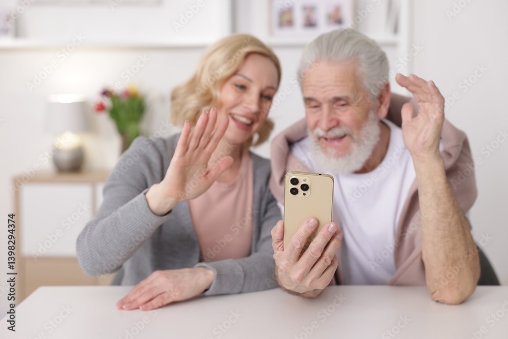 Senior man and mature woman having video chat via smartphone at home, selective focus. Happy couple Senior man and mature woman having video chat via smartphone at home, selective focus. Happy couple