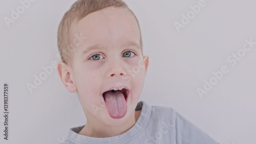 A cheerful young boy playfully sticking out his tongue against a simple background, capturing fun moments.