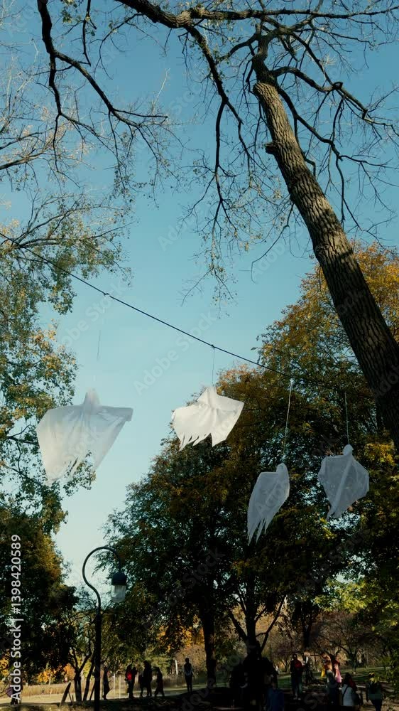 Halloween ghost decor that hanging on the tree at bright sunny day. Vertical view Halloween ghost decor that hanging on the tree at bright sunny day. Vertical view