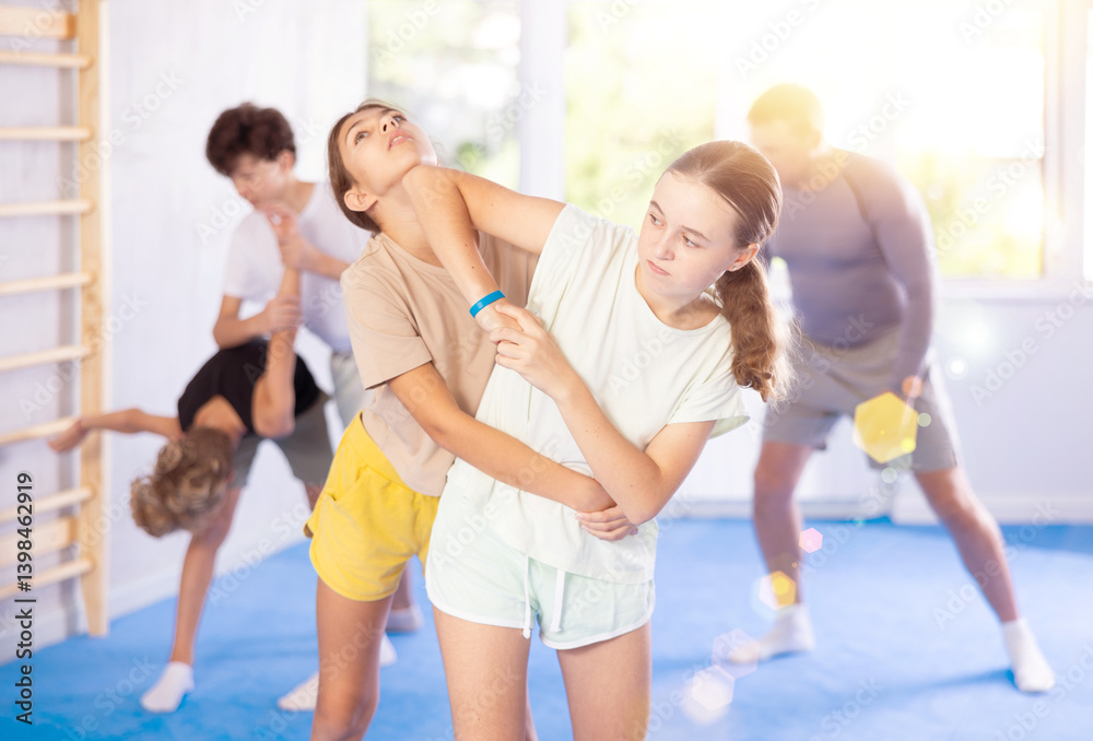 Naklejka premium Two girls training self-defense techniques in group in studio