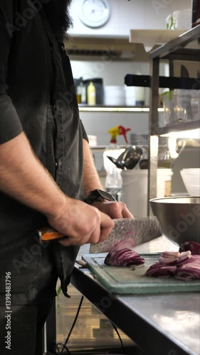 Chef cutting onion on cutting board in restaurant kitchen