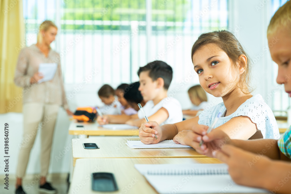 Portrait of cheerful preteen girl elementary school student looking at camera during lesson Portrait of cheerful preteen girl elementary school student looking at camera during lesson