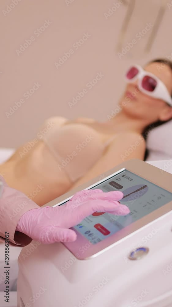 Vertical Format Video of Woman beautician using laser epilation machine in beauty salon. Therapist checking laser hair removal machine at aesthetic clinic.