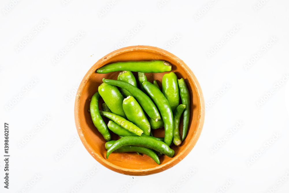 A collection of fresh green chilies displayed in a handmade clay bowl on white background A collection of fresh green chilies displayed in a handmade clay bowl on white background