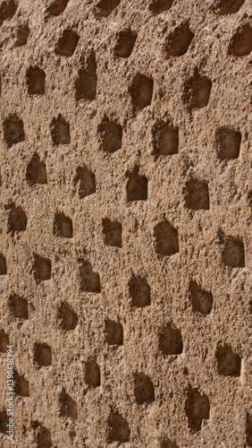 Texture of an old stone wall with small repetitive orifices