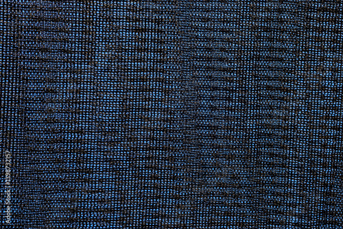 Close-up of black shading mesh against a blue sky. Commonly used in agriculture to protect crops from sunlight