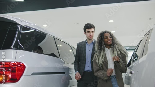Couple exploring vehicles at a modern car dealership while considering options for a new family car during the afternoon